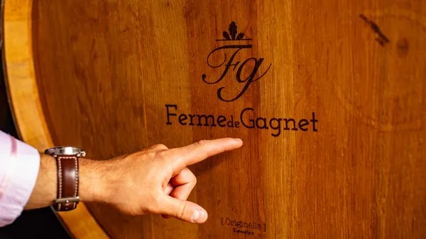 Un fût marqué du logo Ferme de Gagnet dans le chai